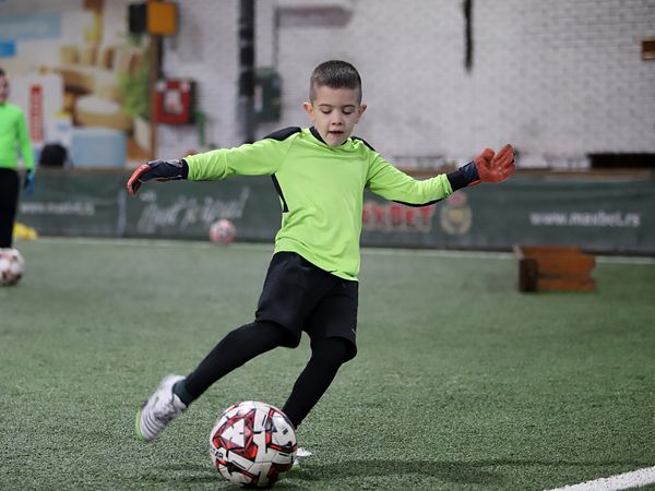 Mladi golman u zelenom dresu šutira loptu
